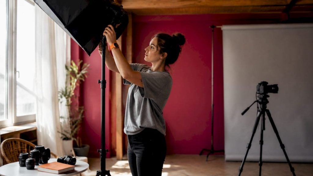 Photographer adjusting studio lighting for portraits